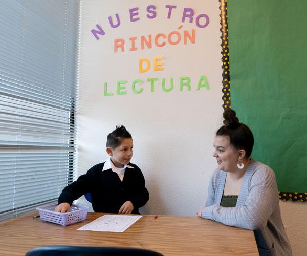 An Arco Iris Spanish Immersion School teacher and student work together on a task at a table.