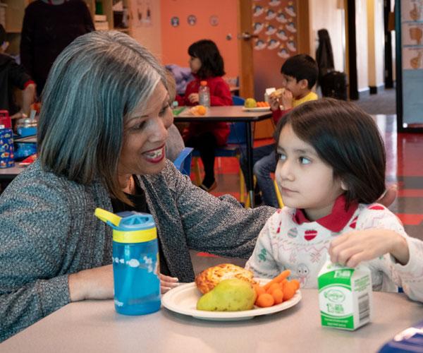 Arco Iris Spanish Immersion School kindergarten teacher Angie Tirado smiles while chatting with a student during lunch.